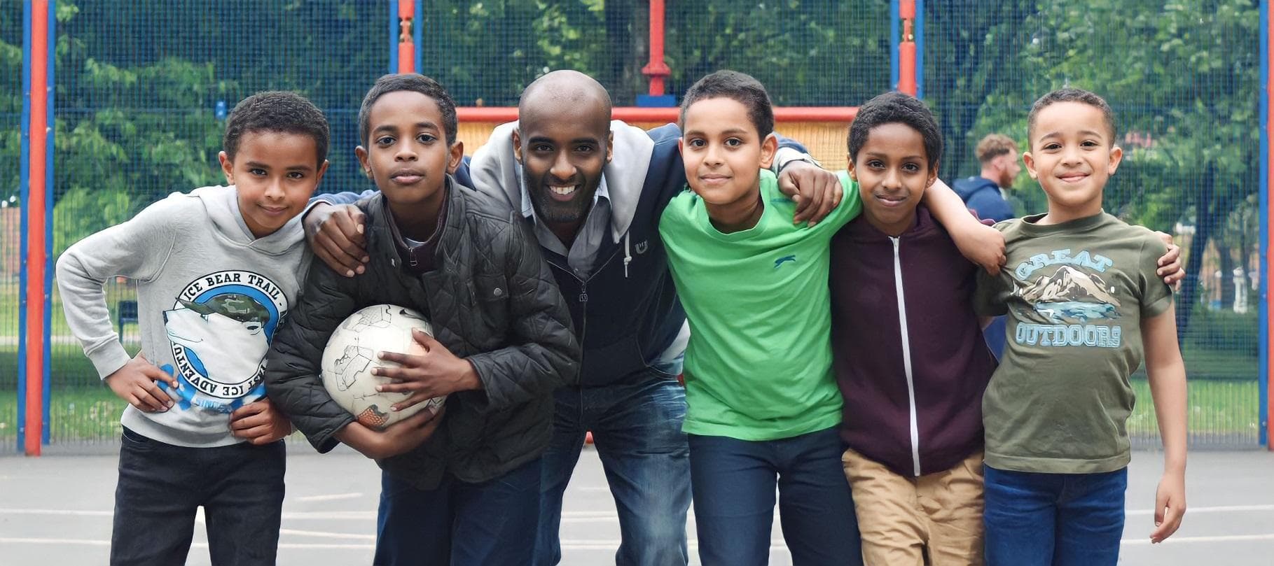 A coach with a group of boys on an outdoor football court