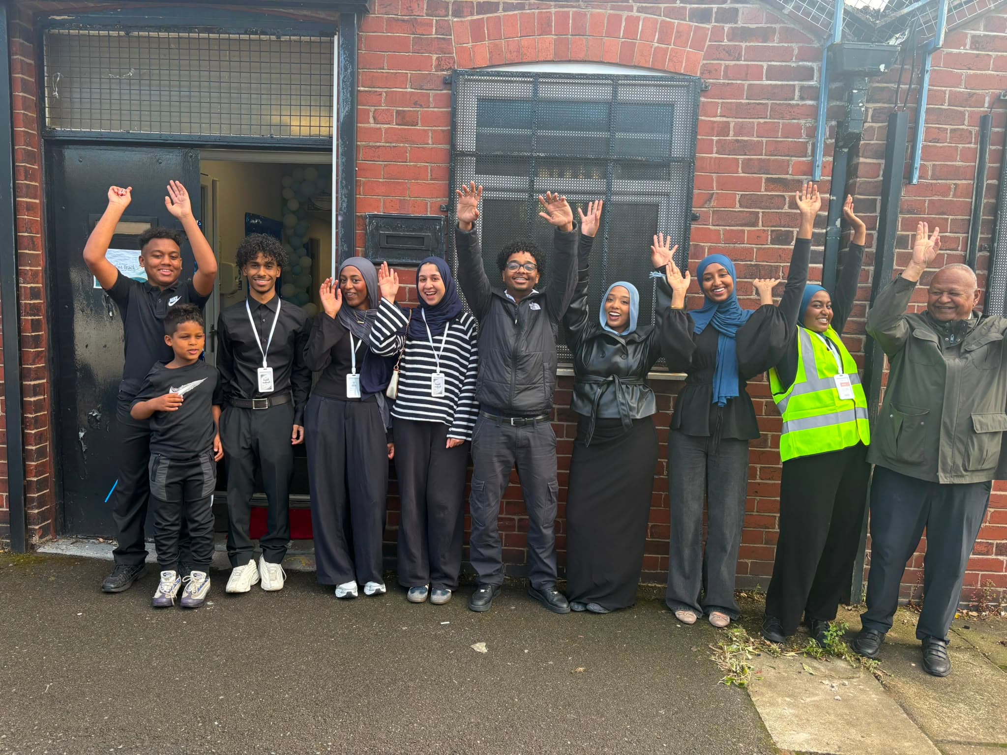 Volunteers and members outside the centre with their hands raised