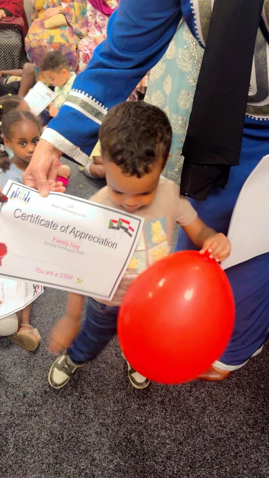 A young child with a balloon and a Family Day certificate