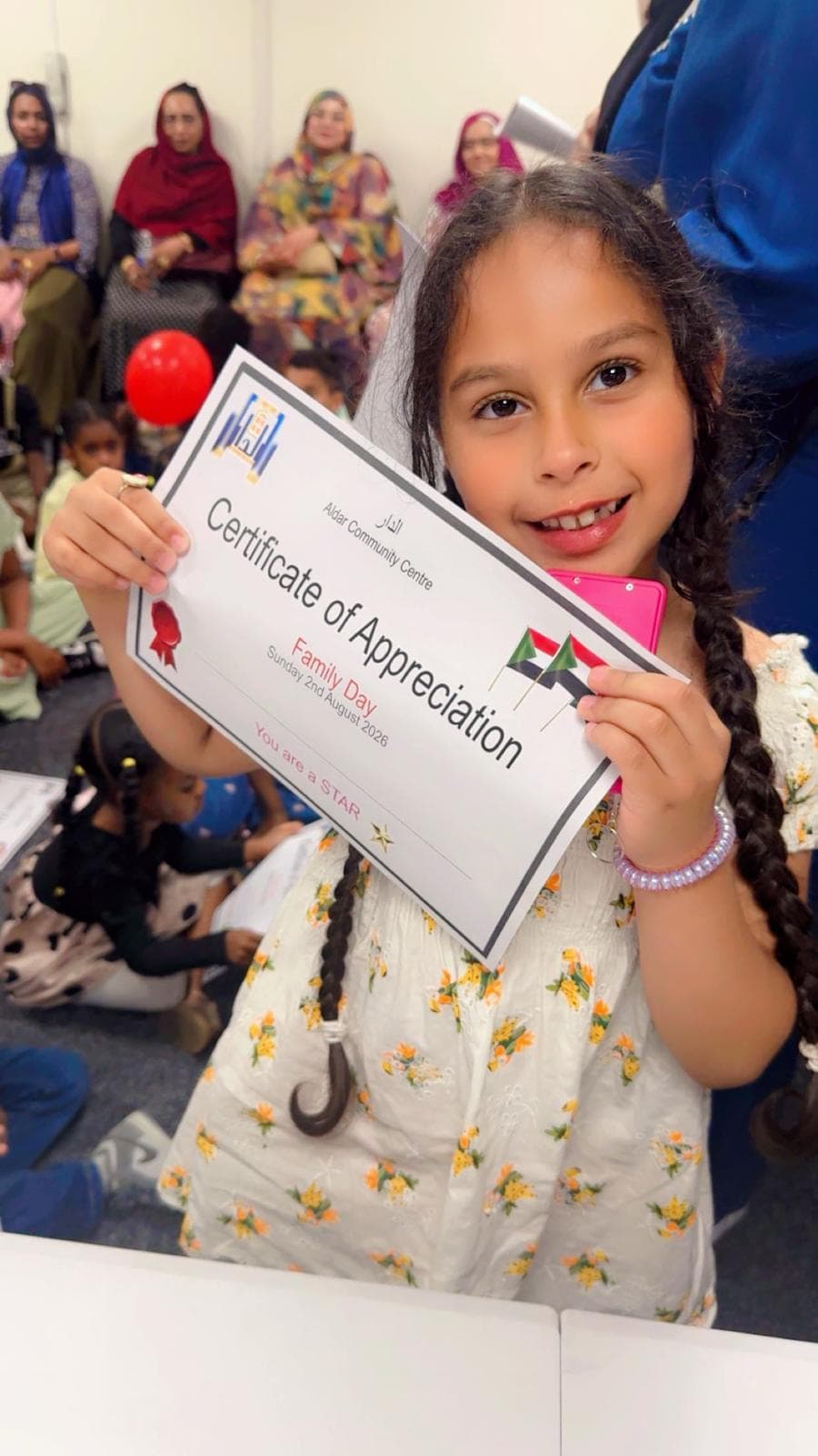 A child holding an Aldar Community Centre certificate of appreciation from Family Day