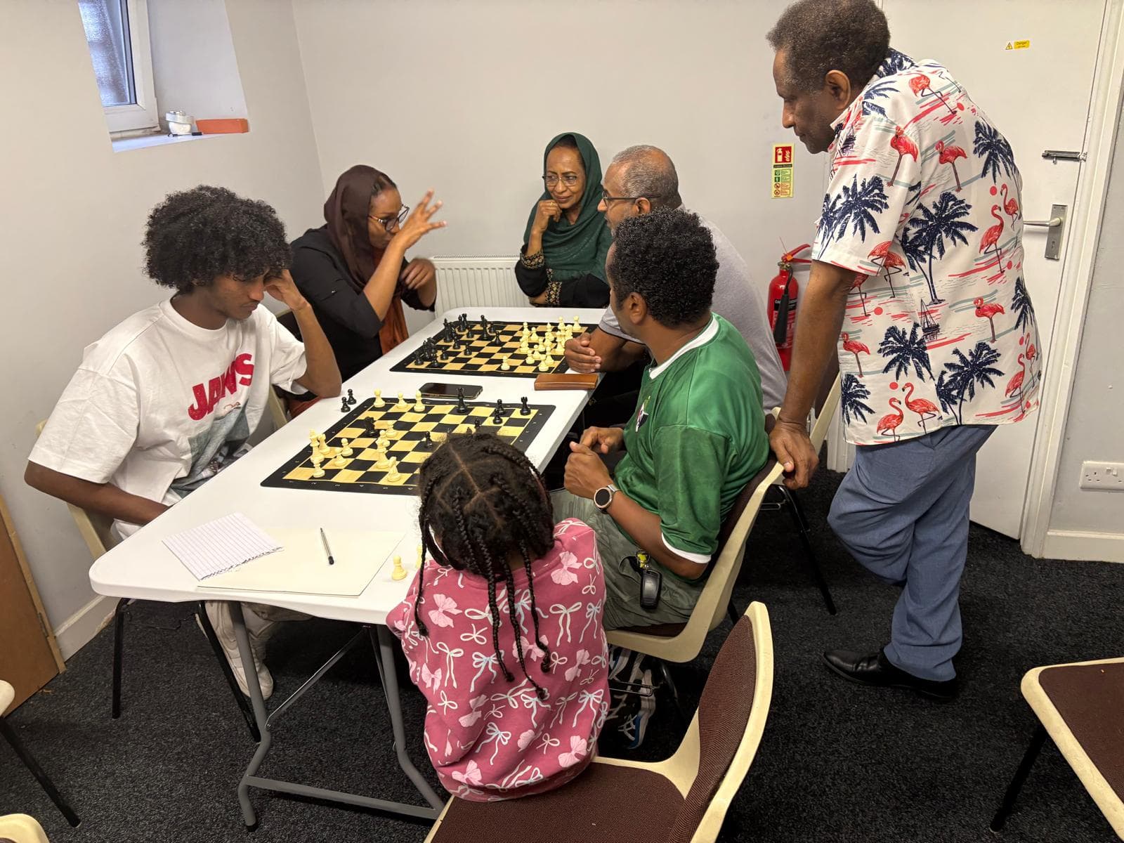 Adults and children playing chess together at the centre