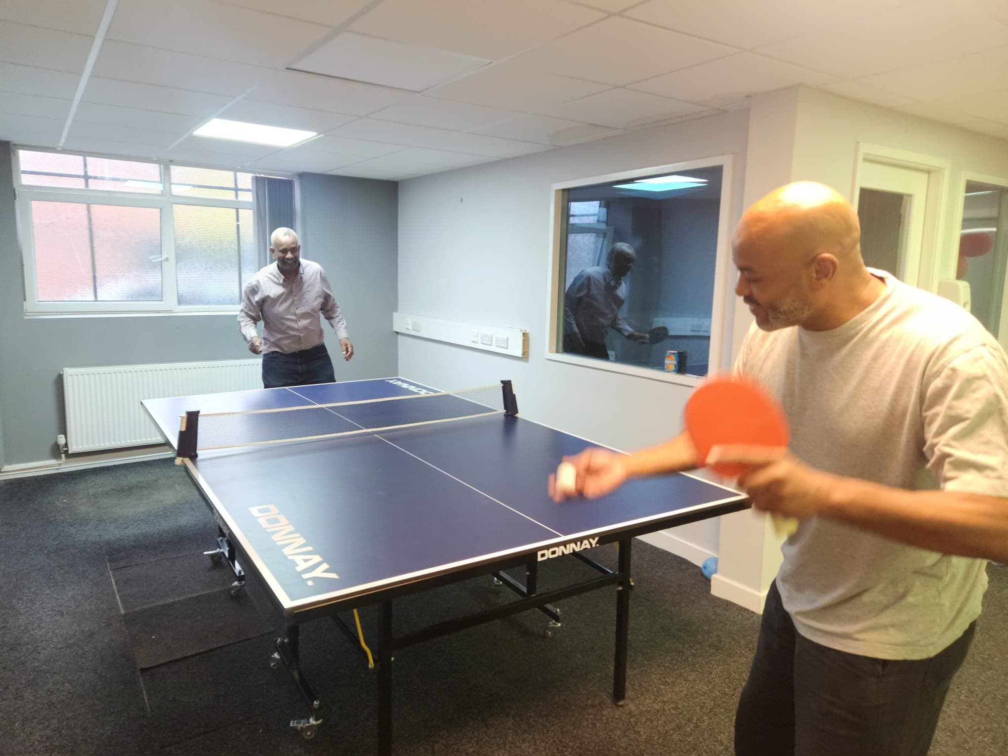 Men playing table tennis in a room at the centre