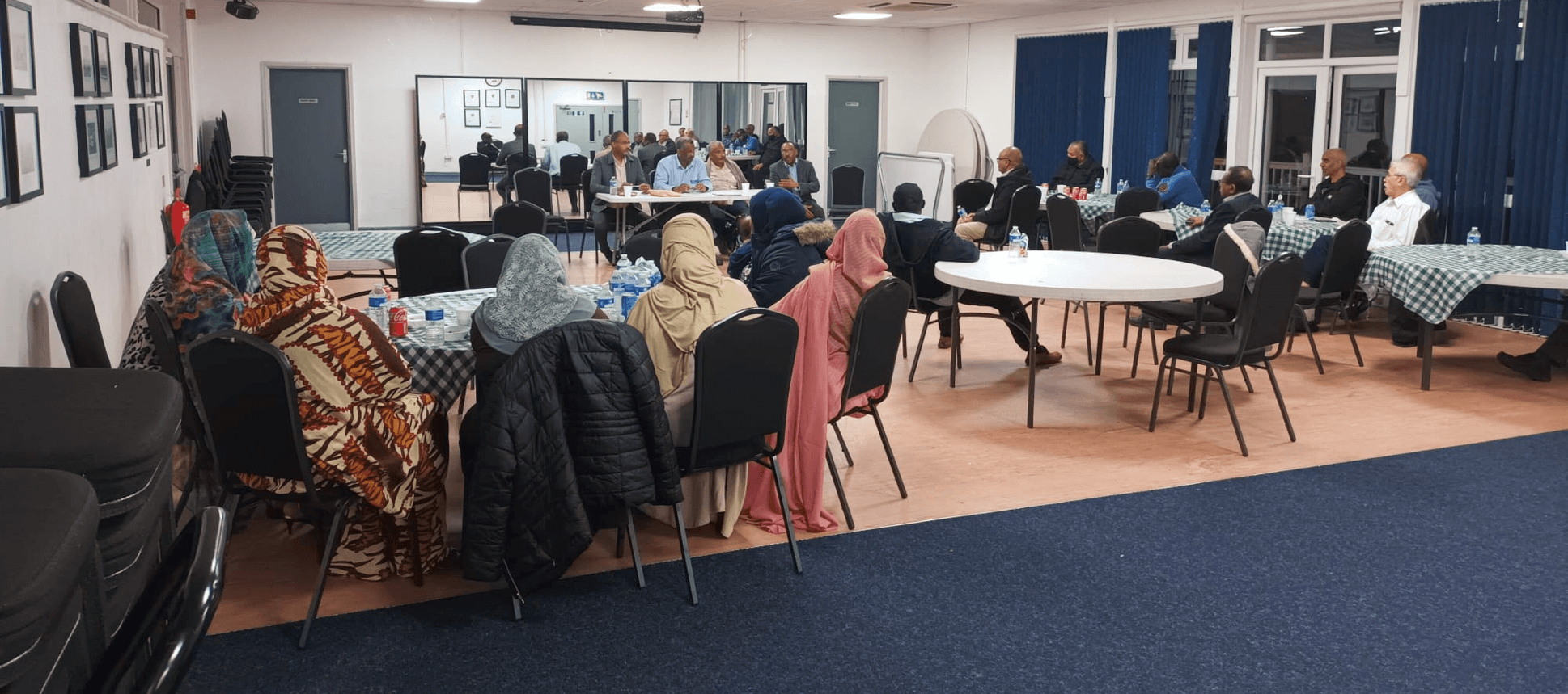 Families seated at tables in the centre's hall
